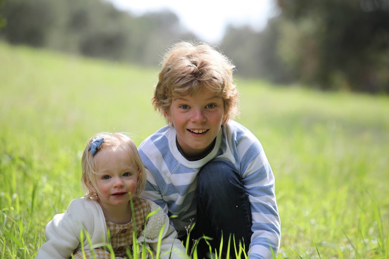 Two siblings laying in the grass.